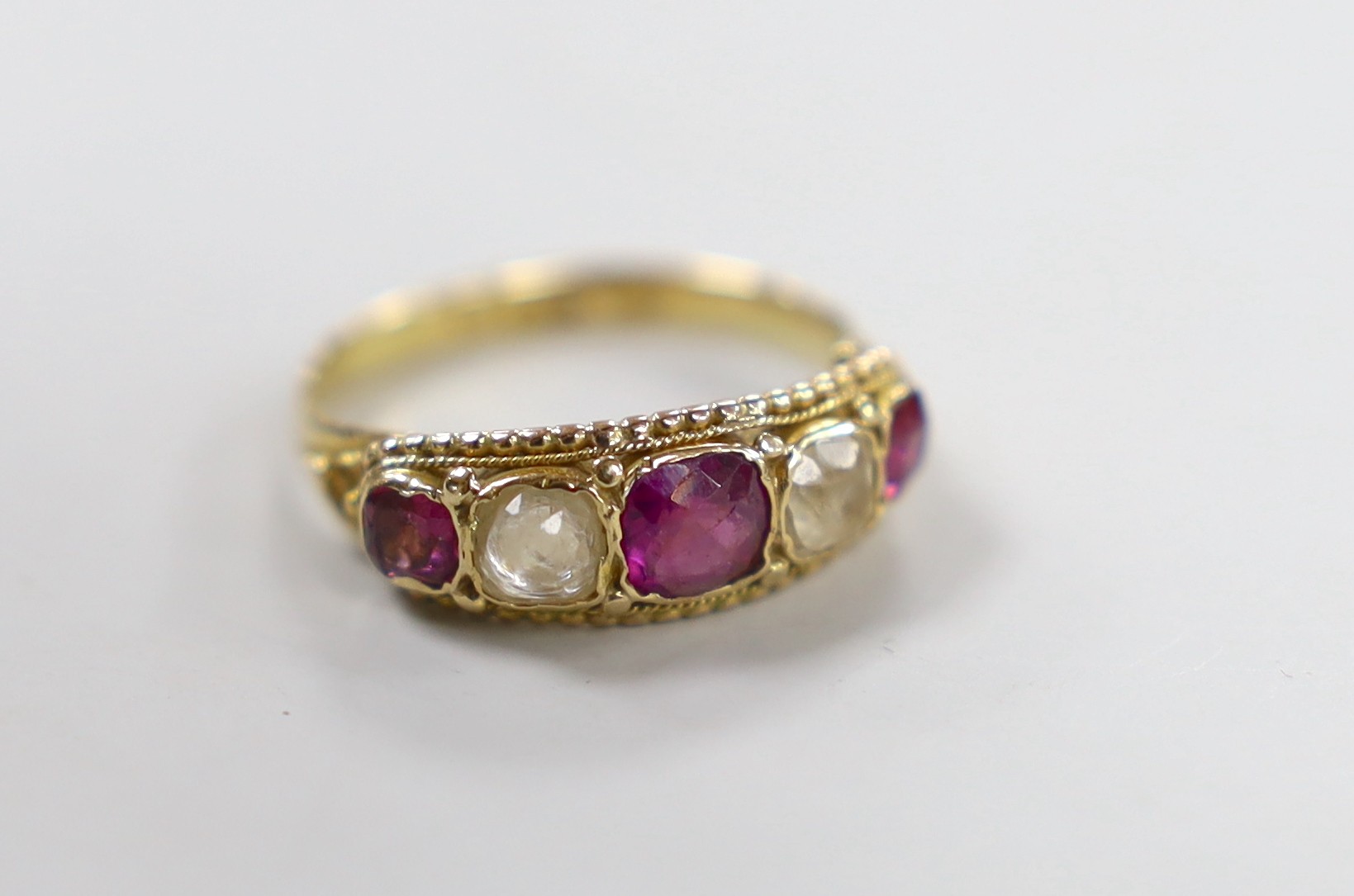 A Victorian 15ct, two stone rock crystal? and three stone garnet set half hoop ring, size L, gross weight 2.2 grams.